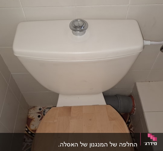 אסלה עם מכסה עץ וצינור מים מחובר